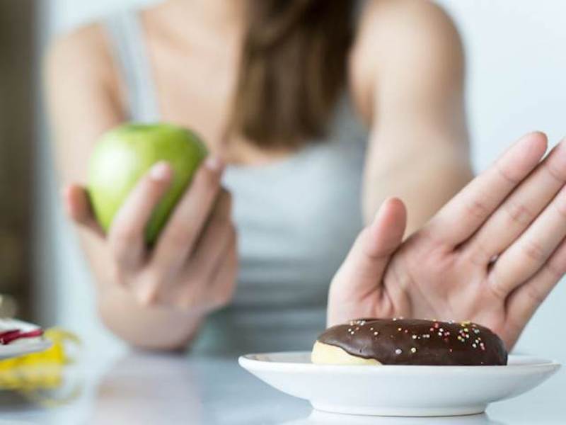 holding an apple saying no to a doughnut, sugar