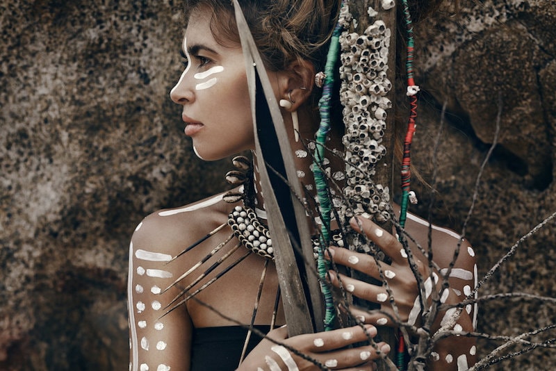 tribal woman portrait with feathers in her hair and white tattoos