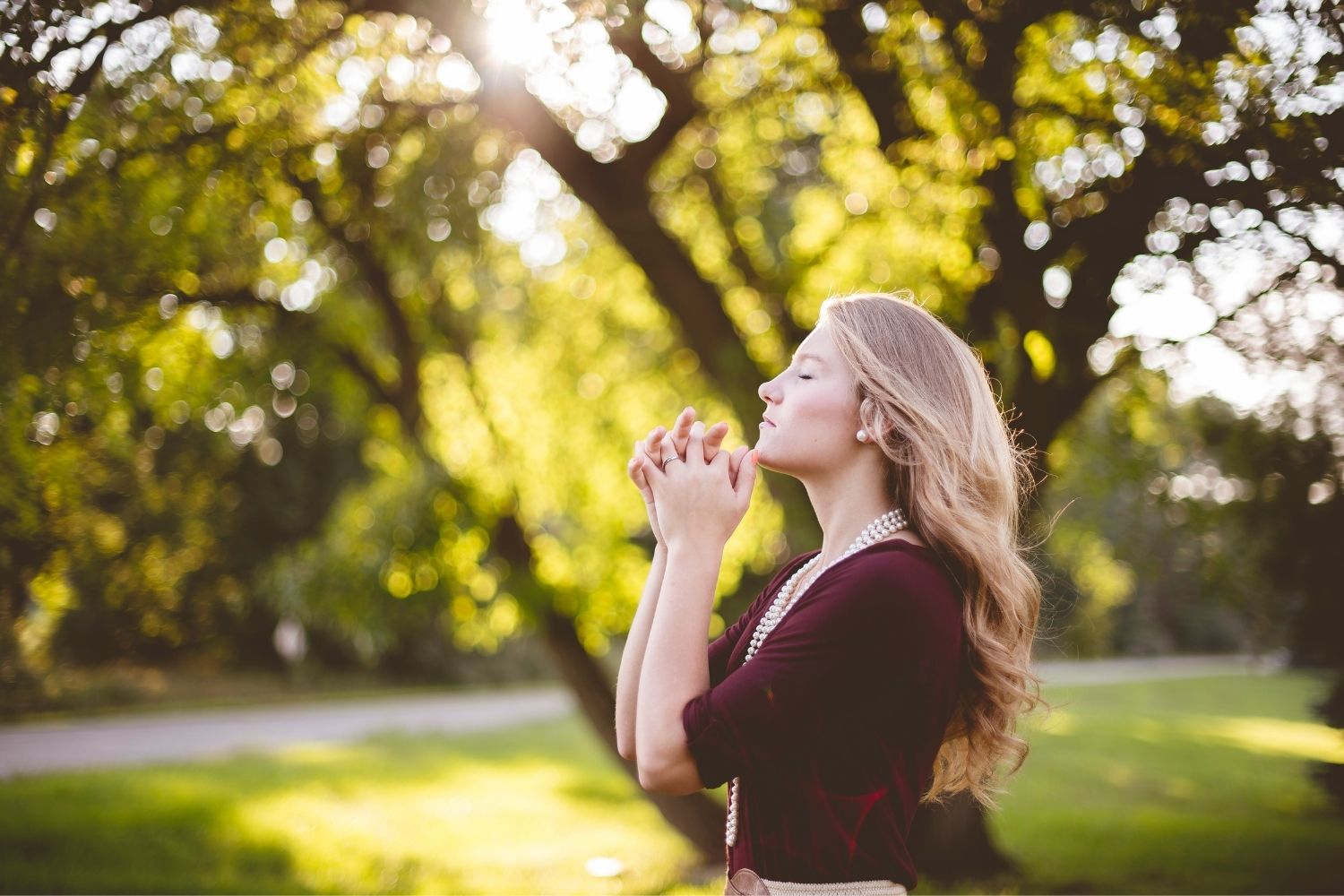 blonde woman praying in the forest