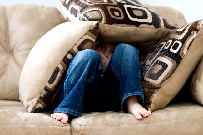 child-boy-hiding-under-cushions