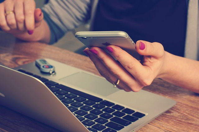 girl checking phone messages at laptop