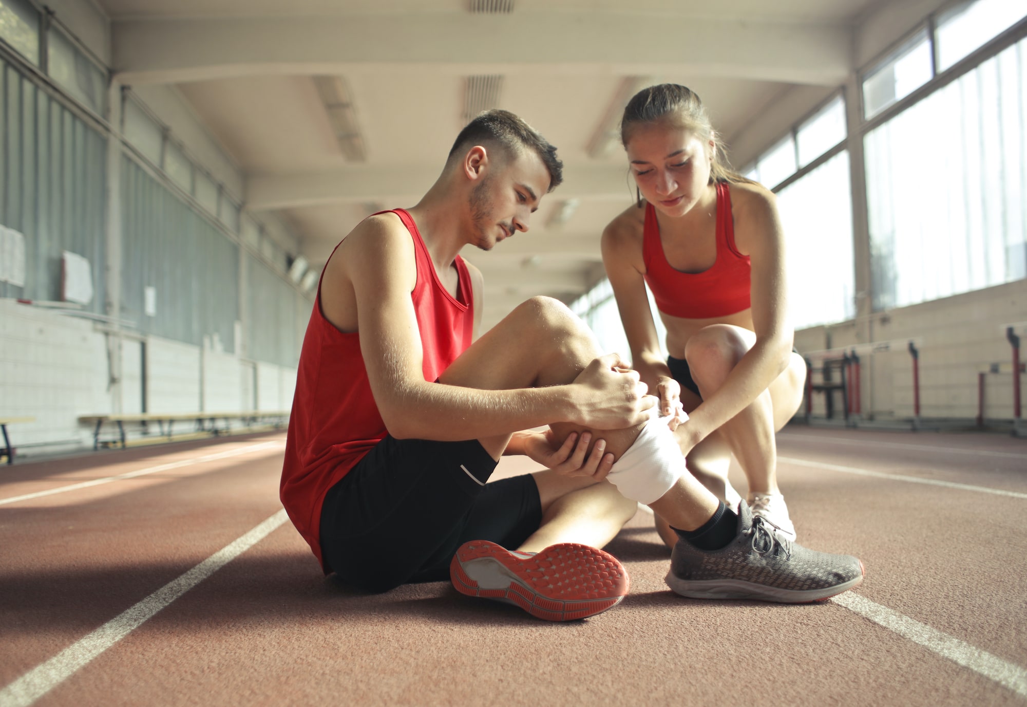 woman helping sportsman with leg injury during cardio exercise